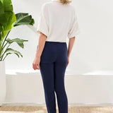 Woman wearing white top with navy ankle pant on a white background