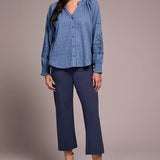 Woman wearing a blue blouse and navy pants against a plain background