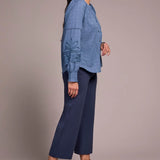Woman wearing a blue shirt and navy pants against a plain background