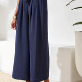 Person wearing navy blue wide-leg pants with a white background