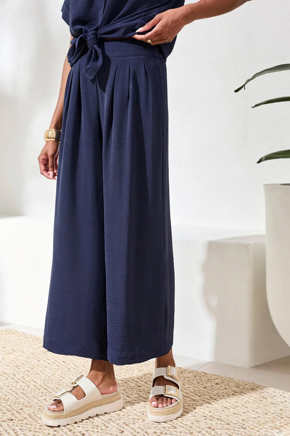Person wearing navy blue wide-leg pants with a white background