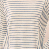 A close-up of a person wearing a long-sleeve crewneck top with thin horizontal blue stripes on a white or off-white base.