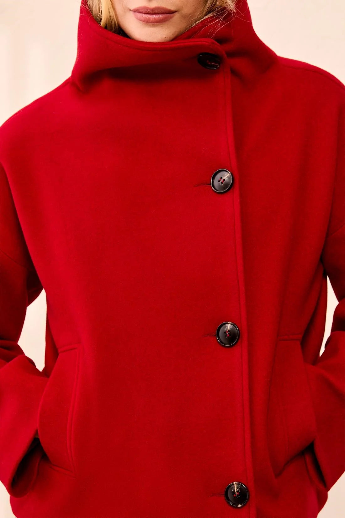 Red coat with black buttons on a neutral background