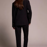 Woman wearing a black suit standing against a plain background