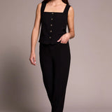 Woman wearing a black sleeveless top and pants against a plain background