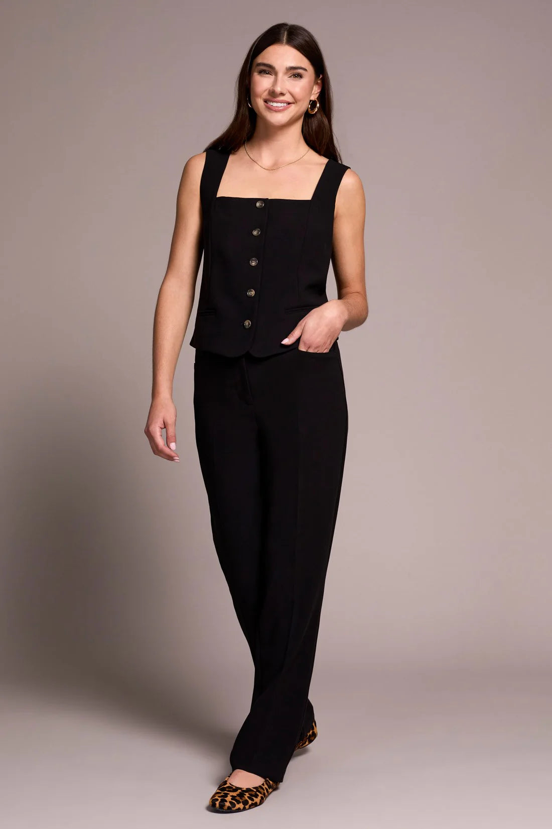 Woman wearing a black sleeveless top and pants against a plain background