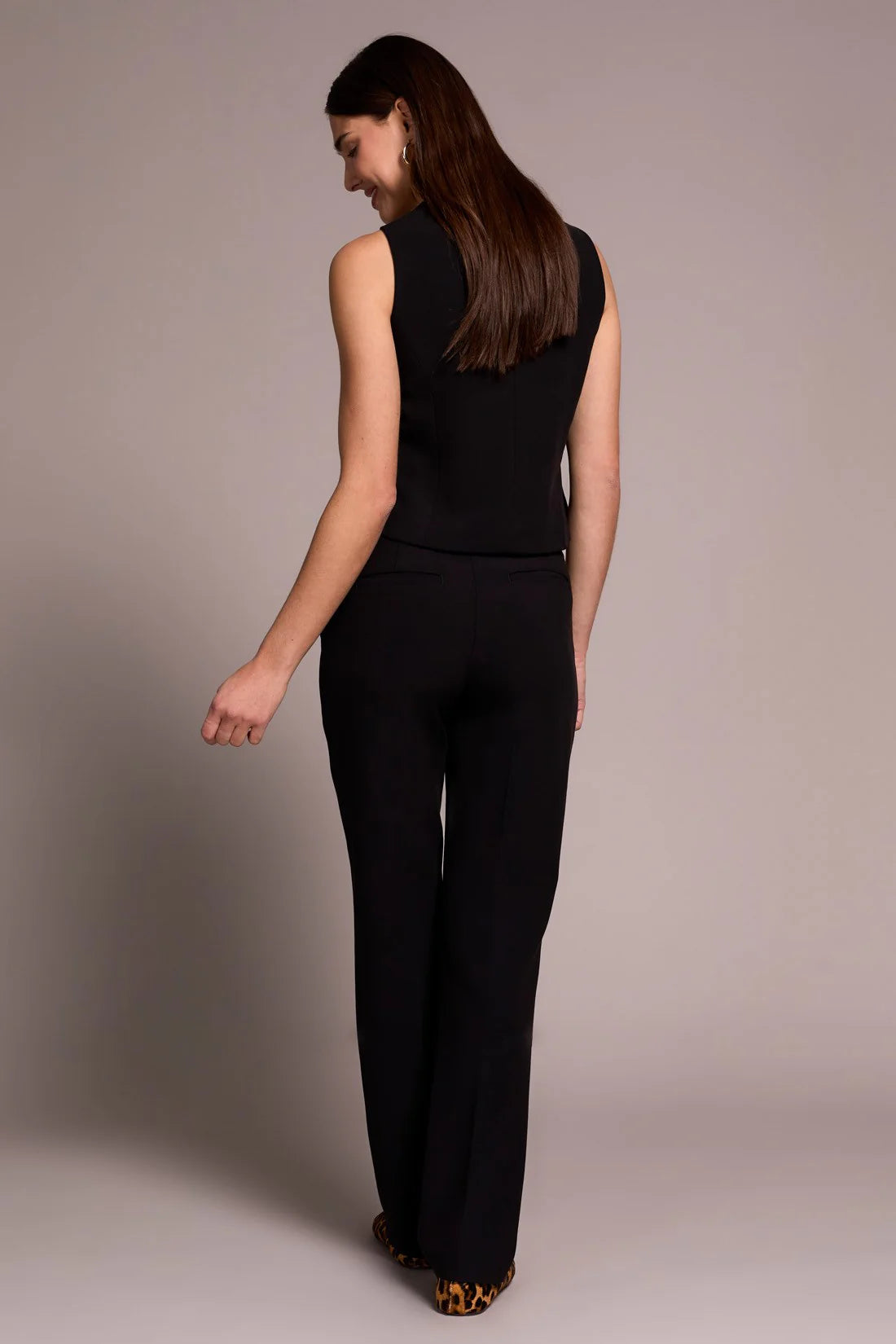 Woman wearing a black sleeveless top and black pants against a plain background
