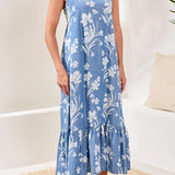Woman wearing a blue floral dress standing on a beige rug with a white wall background