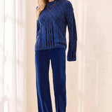 A woman modeling a matching navy blue knit sweater and wide-leg pants set, styled with brown suede shoes in a bright, neutral indoor setting.