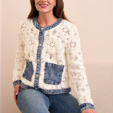 Woman wearing a floral-patterned jacket with denim accents sitting on a couch.