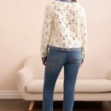 Woman wearing a floral blouse and blue jeans standing in a room with a beige sofa.