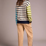 Woman wearing a striped sweater and beige pants against a plain background