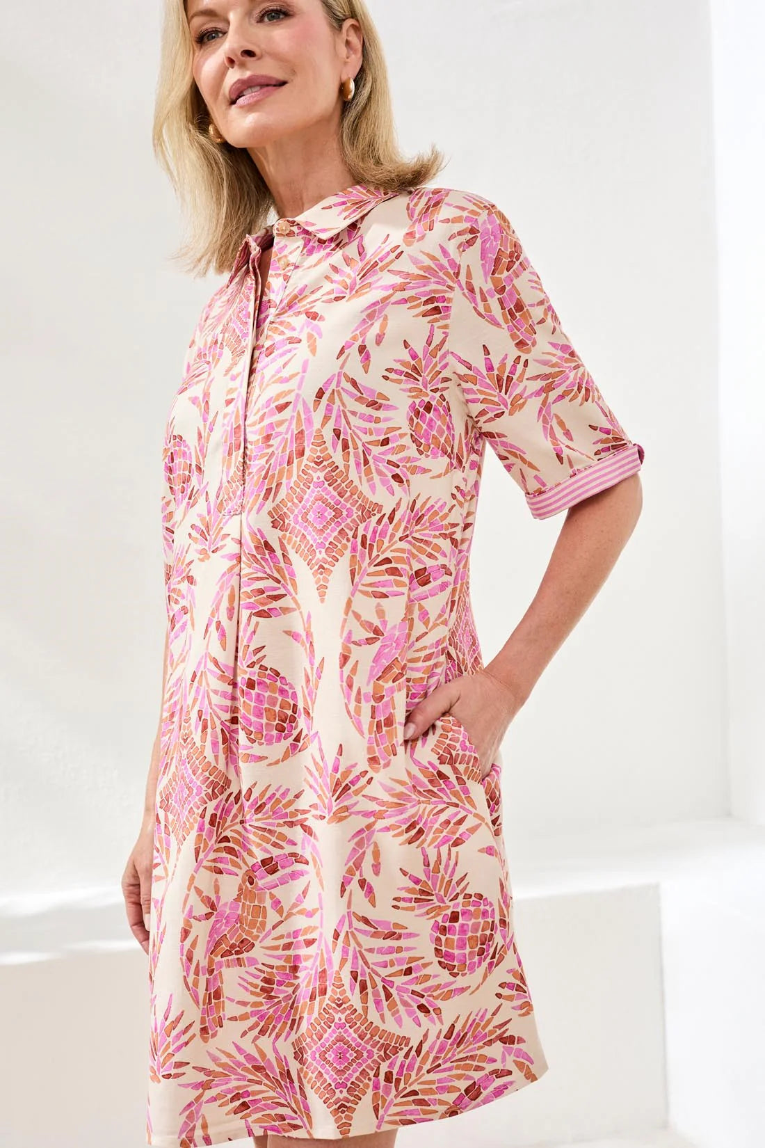 Woman wearing a pink and white patterned dress on a white background