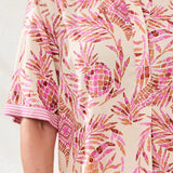 Person wearing a pink and orange patterned dress with a neutral background