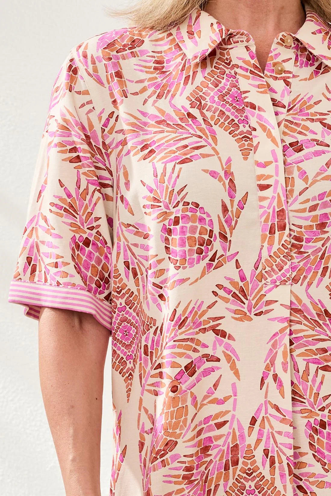 Person wearing a pink and orange patterned dress with a neutral background