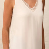 An off-white sleeveless V-neck tank top with delicate lace trim along the neckline and hem, shown on a model.