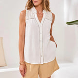 Woman wearing a white sleeveless blouse with beige shorts in a bright setting