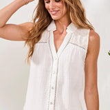 Woman wearing a white sleeveless blouse with a plain background