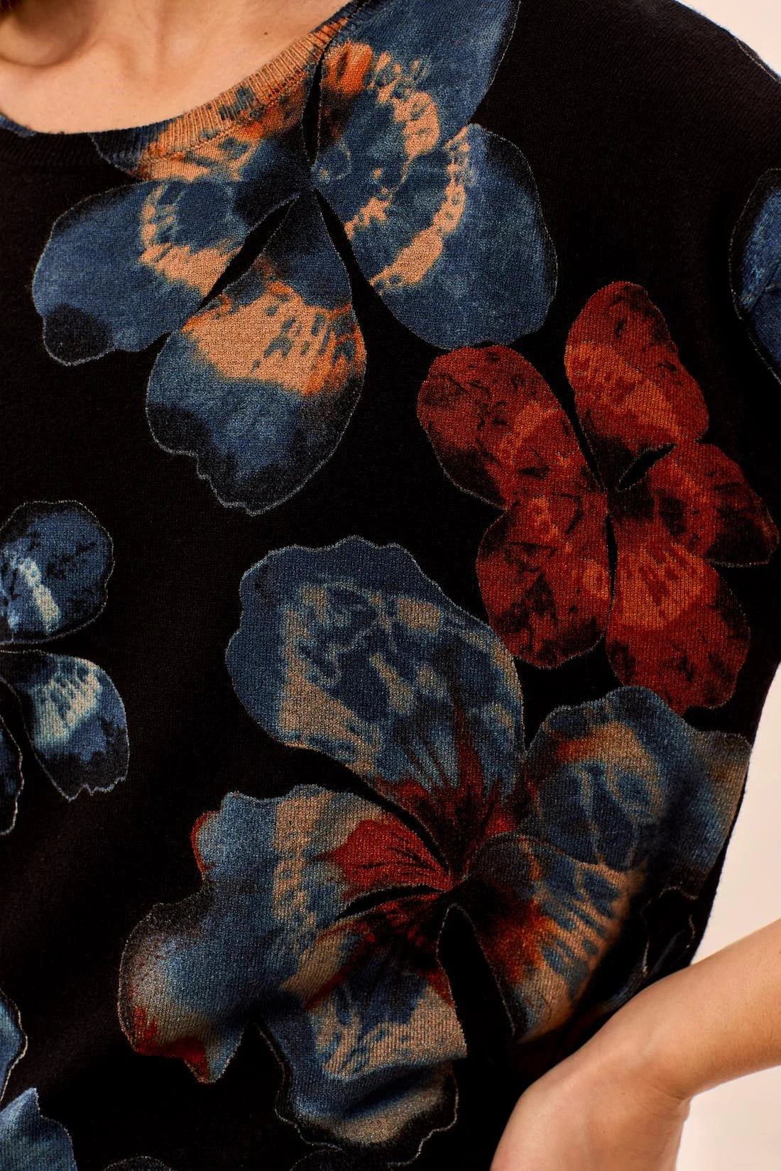 Close-up of a garment with blue and red floral patterns on a dark background
