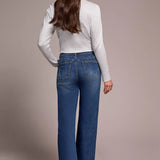Woman wearing blue jeans and a light gray top against a plain background