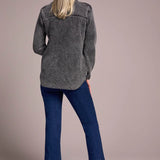 Woman wearing a gray jacket and blue jeans against a beige background