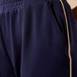 Close-up of navy blue athletic pants with a beige side stripe and a beige waistband, worn with a beige top.