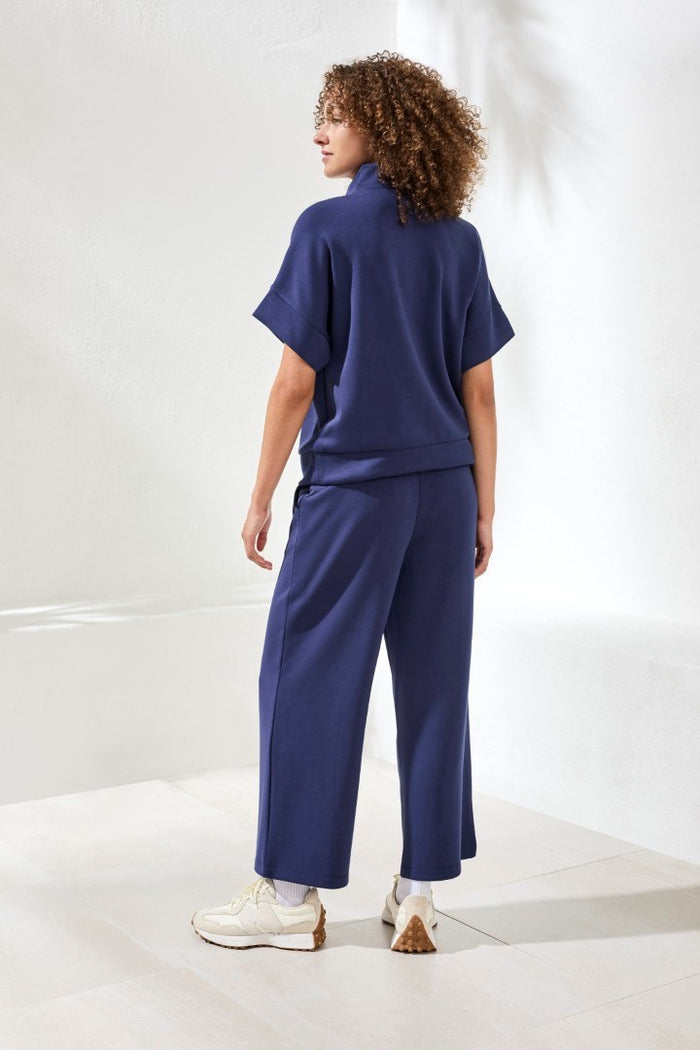 Woman wearing blue short sleeved track suit on white back ground