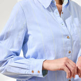 Light blue striped shirt with rolled-up sleeves worn by a person.