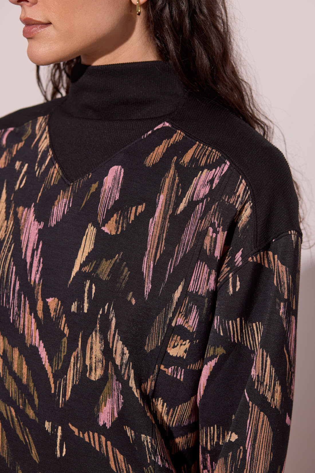 Close-up of a person wearing a black sweater with abstract multicolor pattern.
