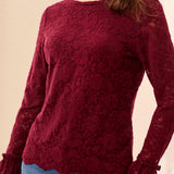 Red lace top worn by a person on a beige background