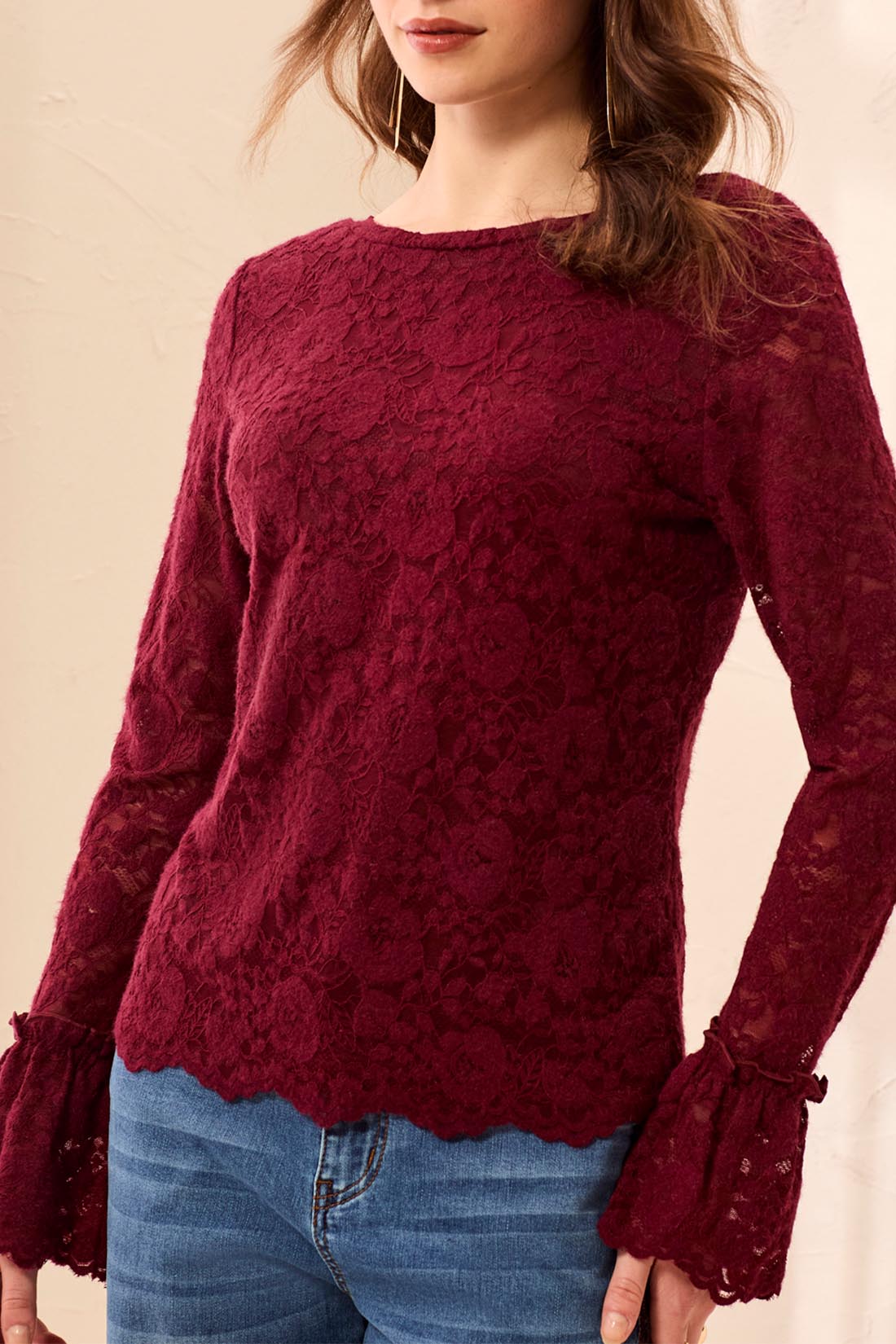 Red lace top worn by a person on a beige background