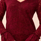 Red lace top worn by a person on a beige background
