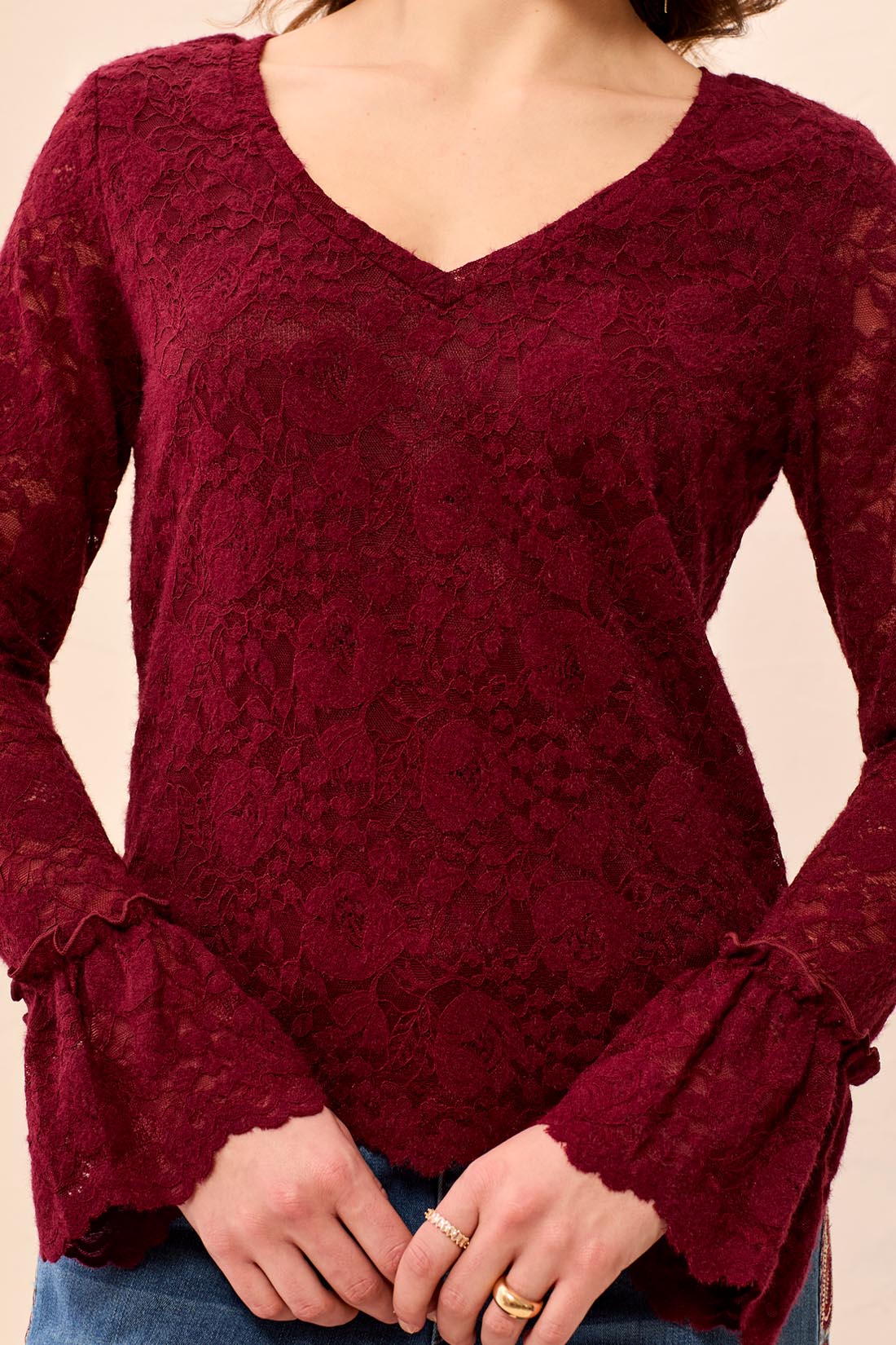 Red lace top worn by a person on a beige background
