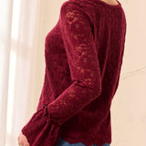 Red lace top worn by a person on a beige background