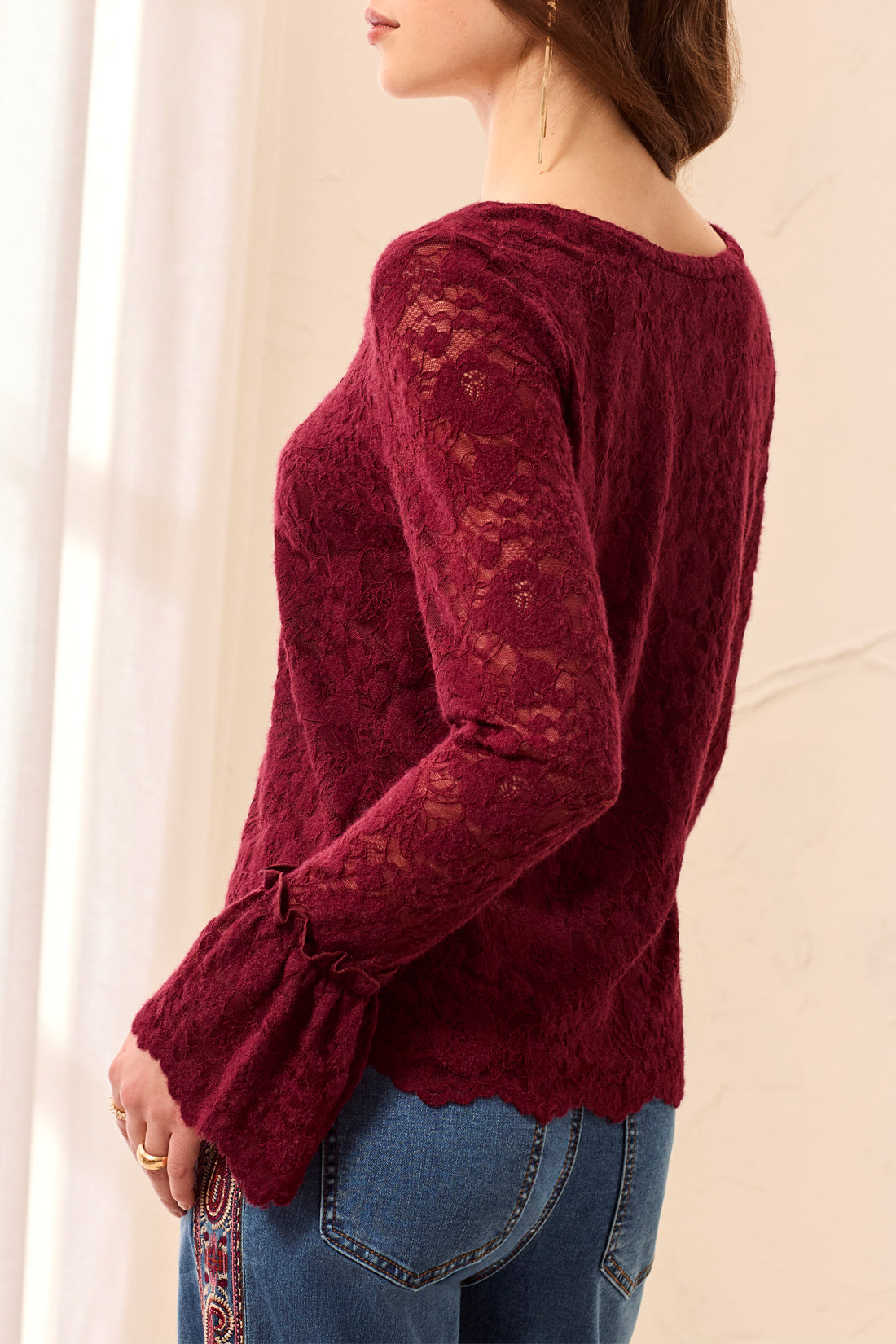 Red lace top worn by a person on a beige background