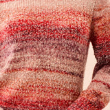 Close-up of a person wearing a multicolored knit sweater with a blurred background