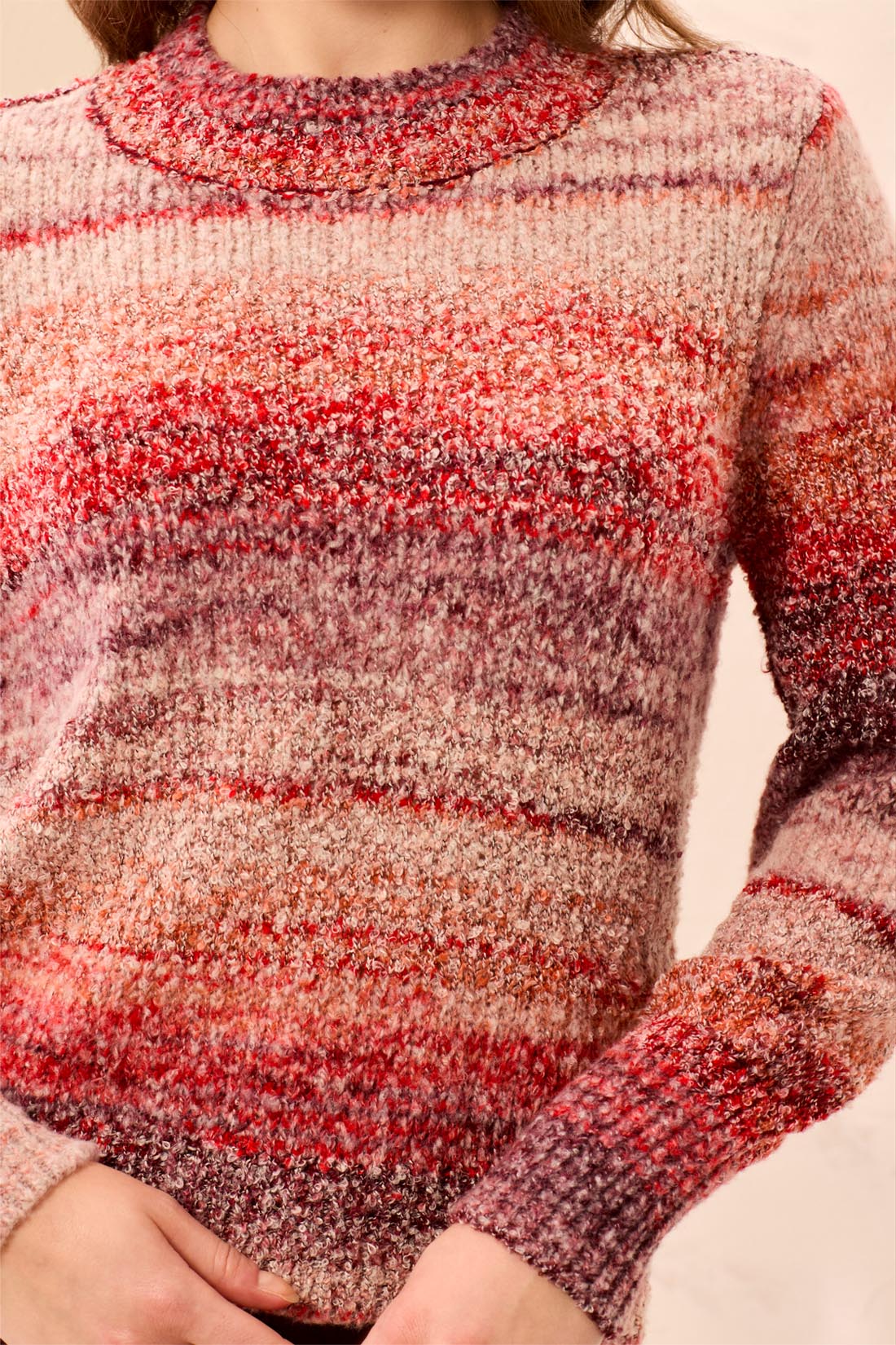 Close-up of a person wearing a multicolored knit sweater with a blurred background