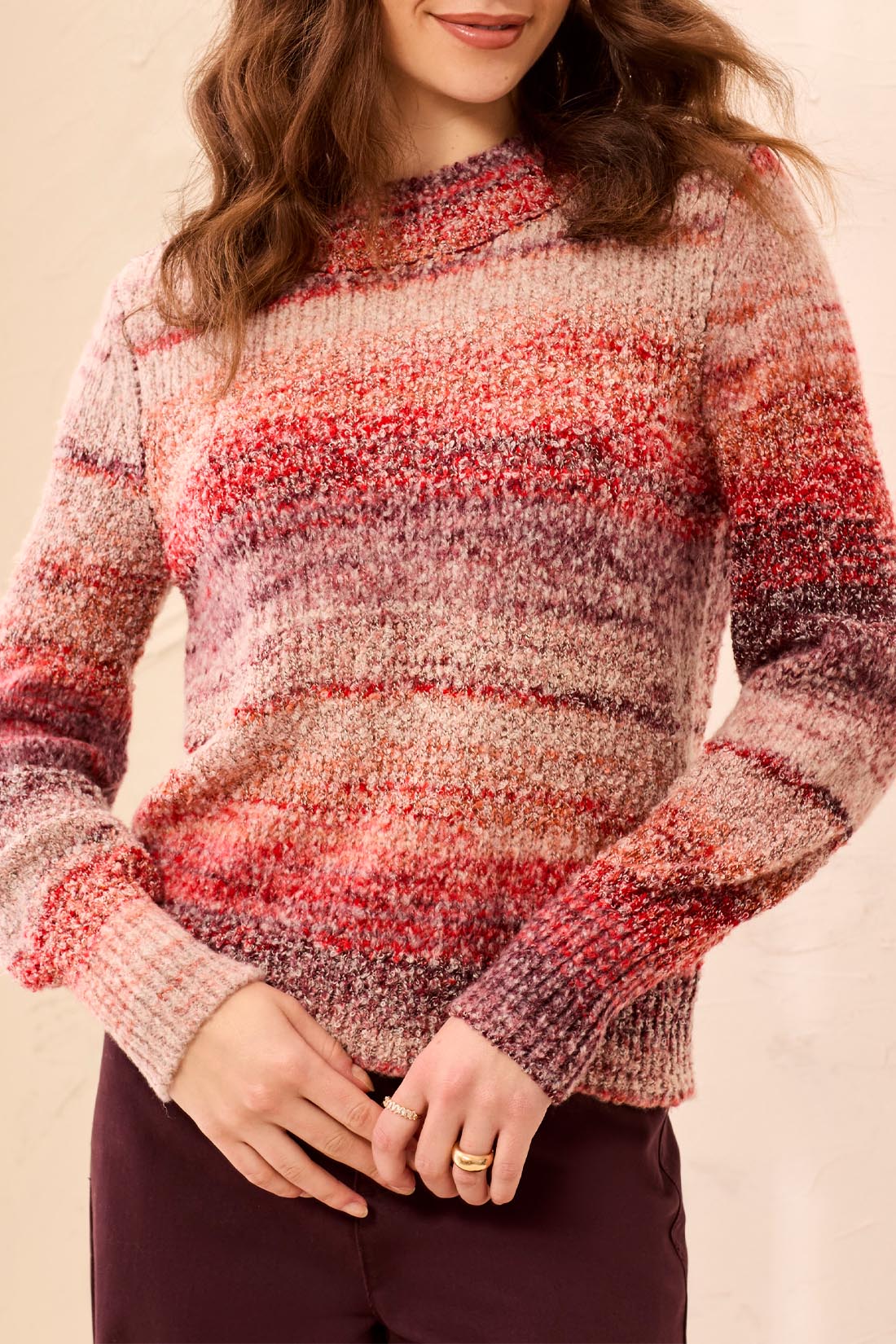 Person wearing a multicolored striped sweater against a beige background