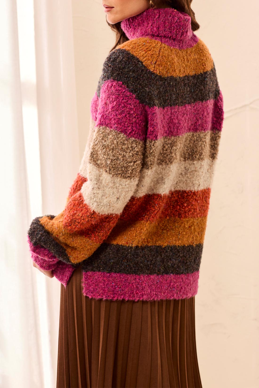 Colorful striped sweater worn by a person with a neutral background