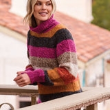 Woman wearing a colorful striped sweater standing on a balcony.