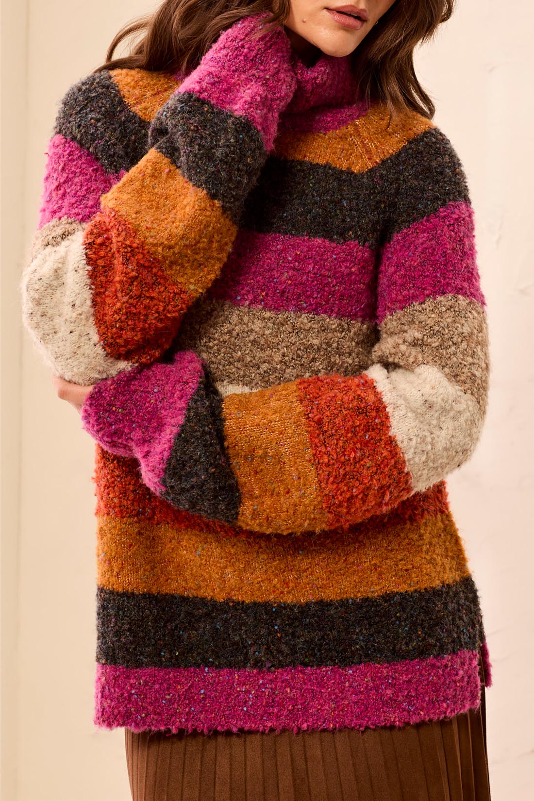 Multicolored striped sweater worn by a person on a beige background