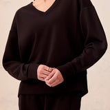 Person wearing a black outfit against a beige wall