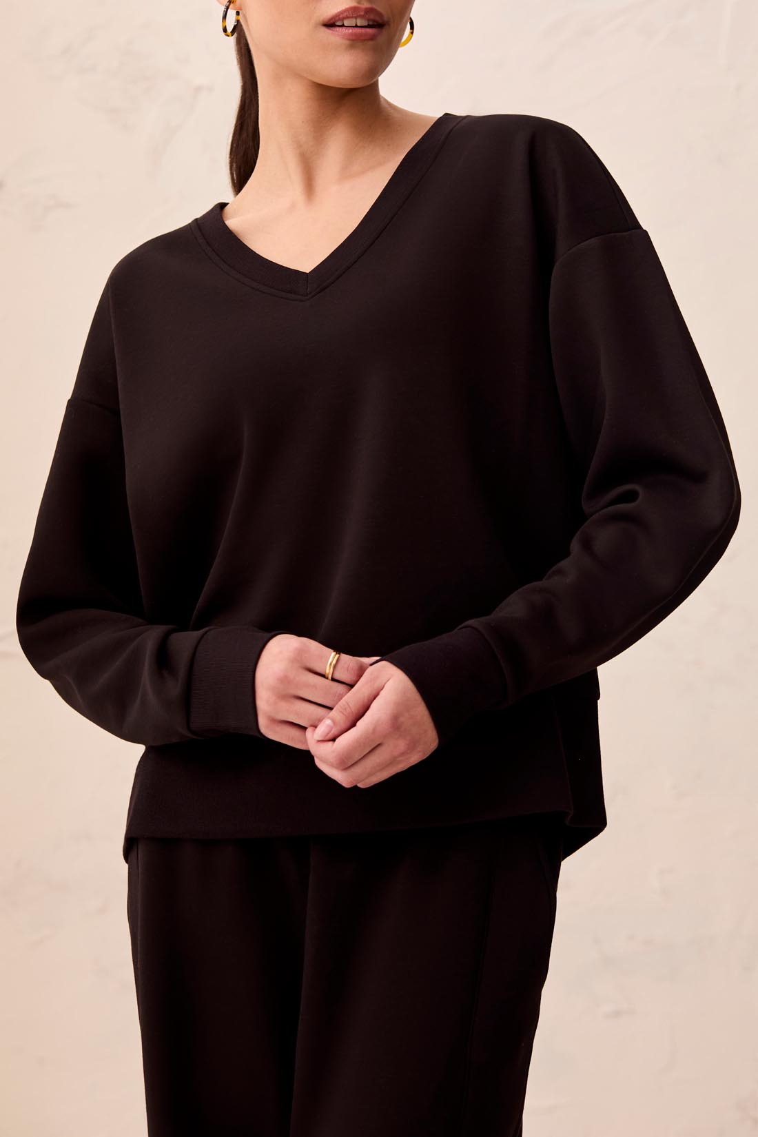 Person wearing a black outfit against a beige wall