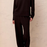 Person wearing a black outfit against a beige wall