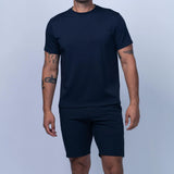 Man wearing a navy blue t-shirt and shorts on a light gray background