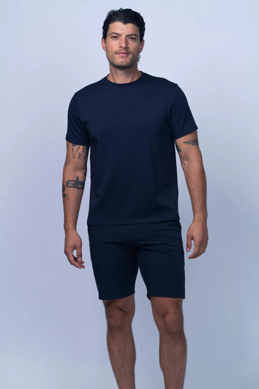 Man wearing a navy blue t-shirt and shorts on a light gray background