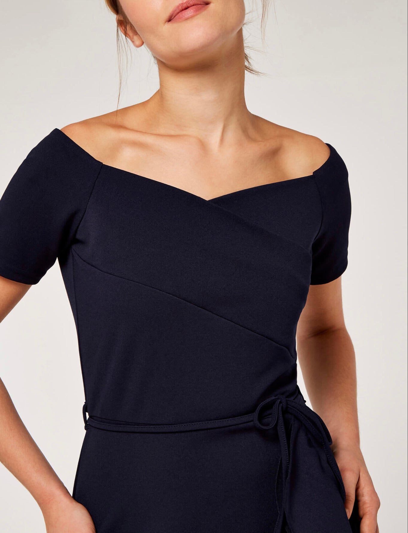 This dress features delicate frills, a romantic Bardot neckline, and a flattering fit.